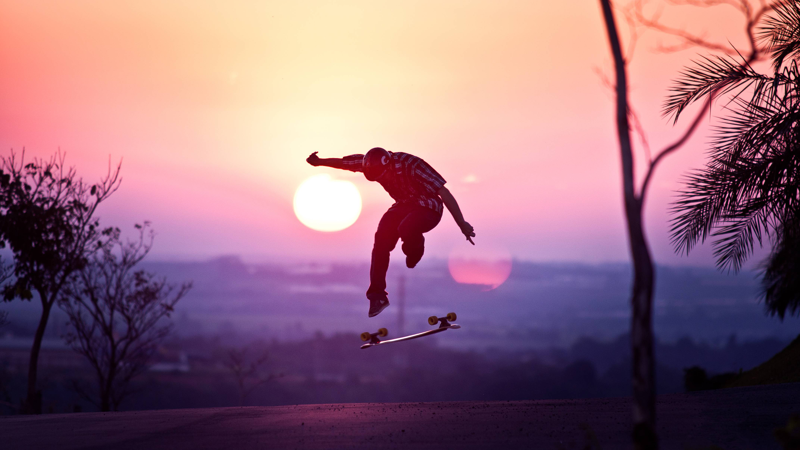 A skater kickflipping at sunset